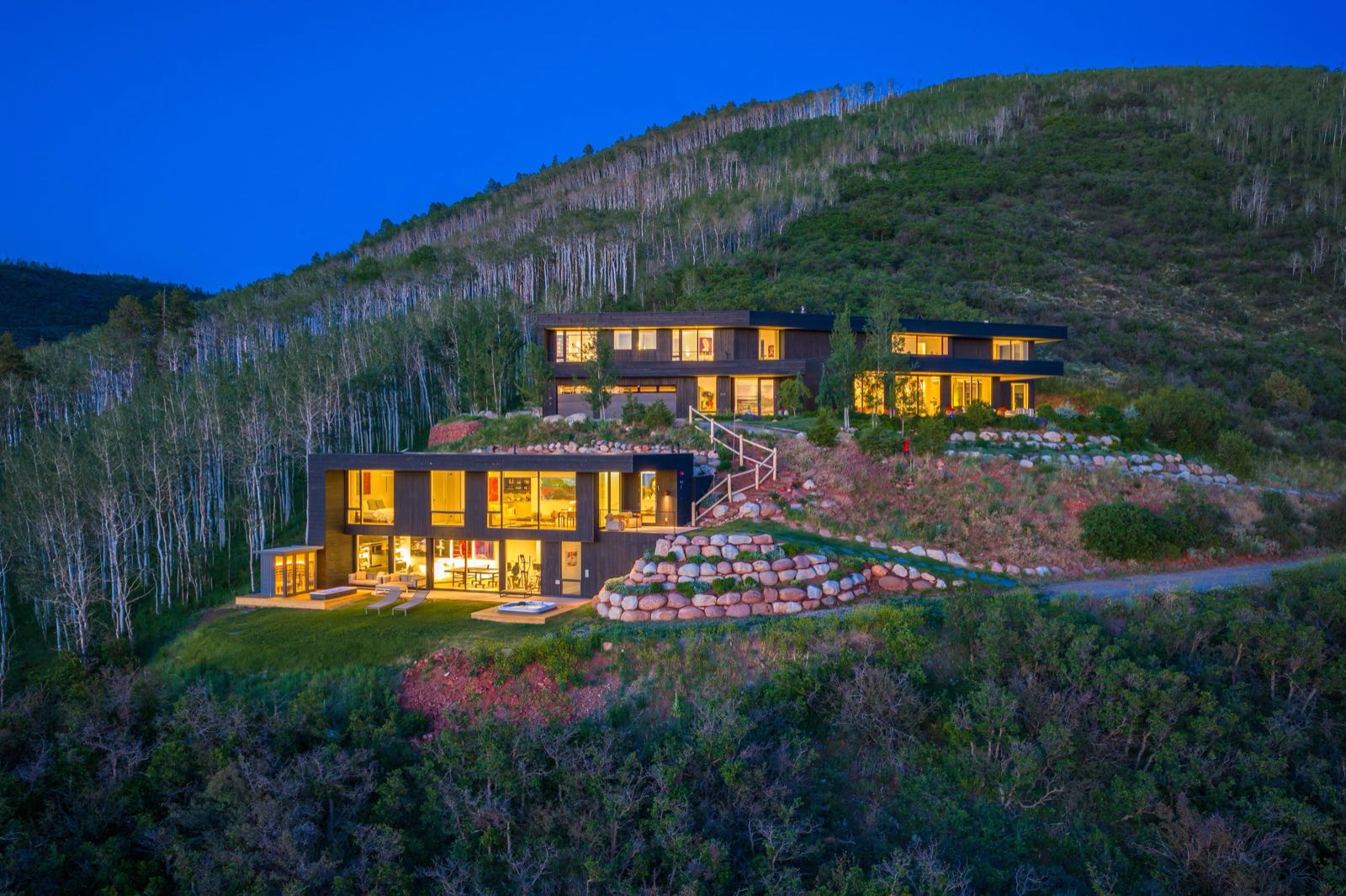 Twilight aerial of 542 Carroll Drive · main house and guest house glowing on the Starwood hillside